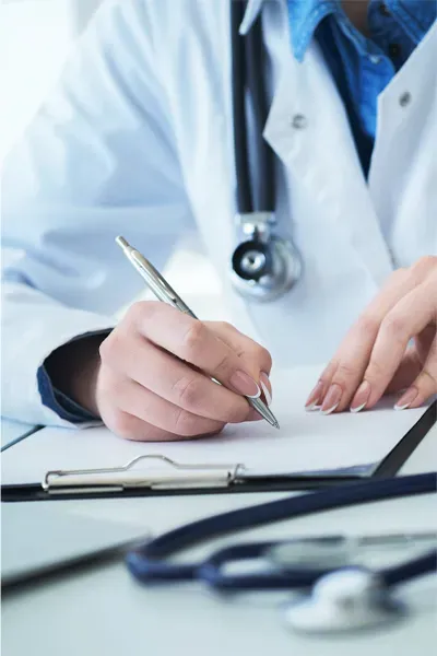 Advanced-Diagnostic-Testing-Treatment Close up of a doctor in a white coat, writing on a notepad, representing functional medicine testing offered by Optimal Wellness Medical Group in Grand Rapids.