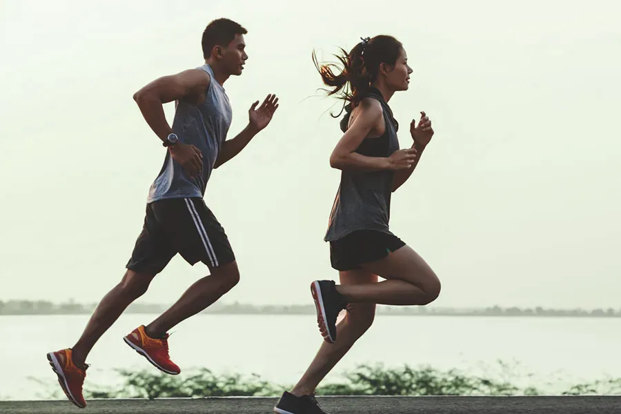 GLP-1-Weight-Loss-Injections-Clinic A couple in profile running along the water. Schedule GLP-1 Weight Loss Injections from Optimal Wellness Medical Group in Grand Rapids.