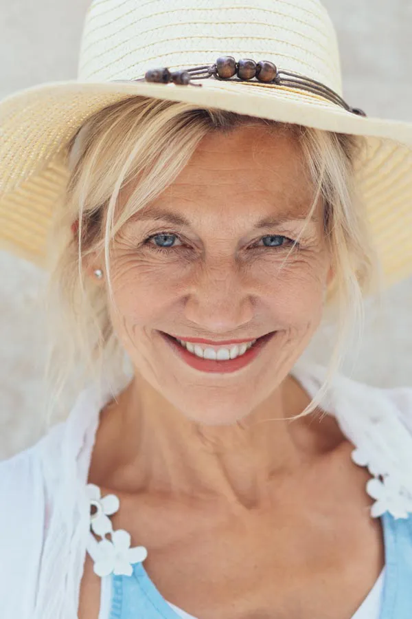 Menopause-Treatment A beautiful, smiling older woman with blonde hair and a sunhat, happy with menopause treatment from Optimal Wellness Medical Group in Grand Rapids.