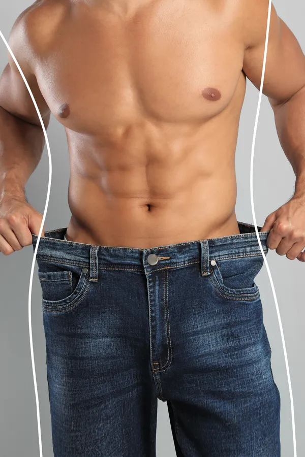 Semaglutide-Weight-Loss-Treatment A strong shirtless man in jeans holds the waistlines of his too-big jeans to show the success of semaglutide weight loss from Optimal Wellness Medical Group in Grand Rapids.