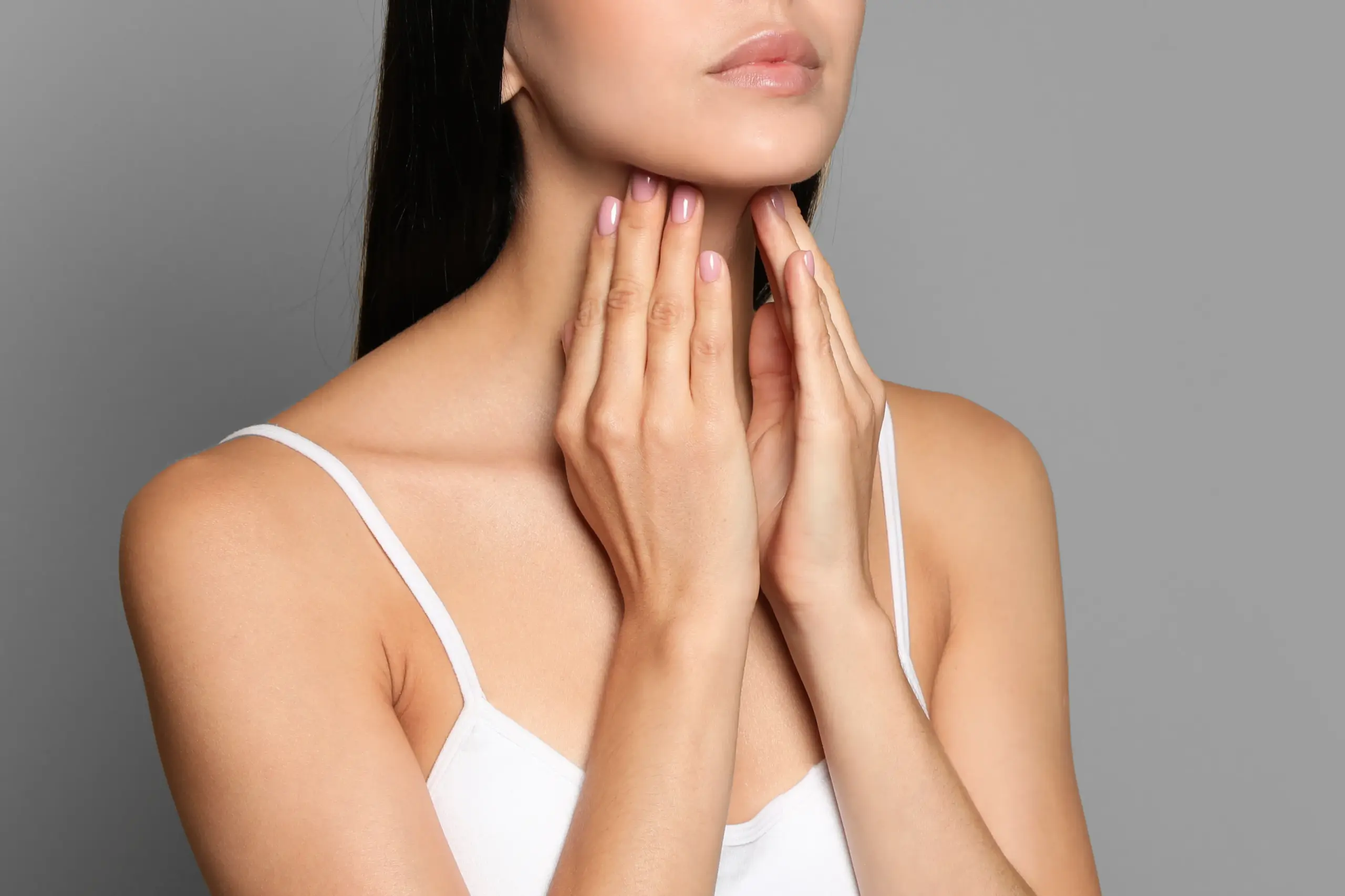 Thyroid-Doctor A woman in a white tank top touches her neck looking for signs of thyroid disorder. Get help for thyroid disorders from Optimal Wellness Medical Group in Grand Rapids.