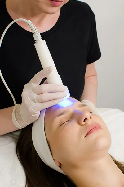 grand-rapids-light-therapy-facials Close up of an aesthetician performing a light therapy facial on a relaxing woman. Schedule your Light Therapy for Skin appointment with Optimal Wellness Medical Group in Grand Rapids today.