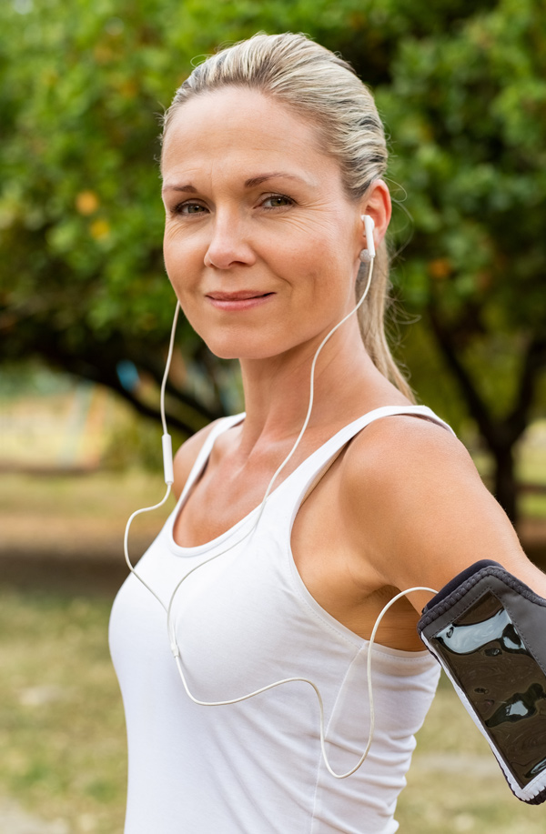 fibromyalgia-doctor Middle-aged, active woman taking a break to smile at the camera during a run, representing successful Bioidentical Hormones for Fibromyalgia Relief offered by Optimal Wellness Medical Group in Grand Rapids.
